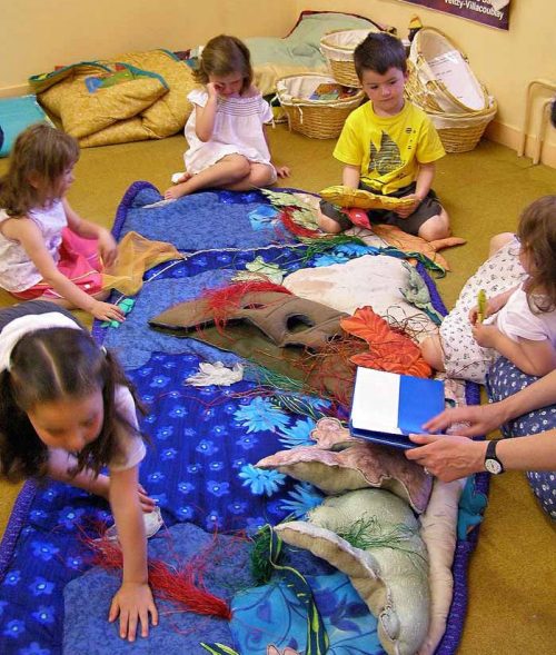 A facilitator with little ones around the raconte-tapis MER BLEUE.